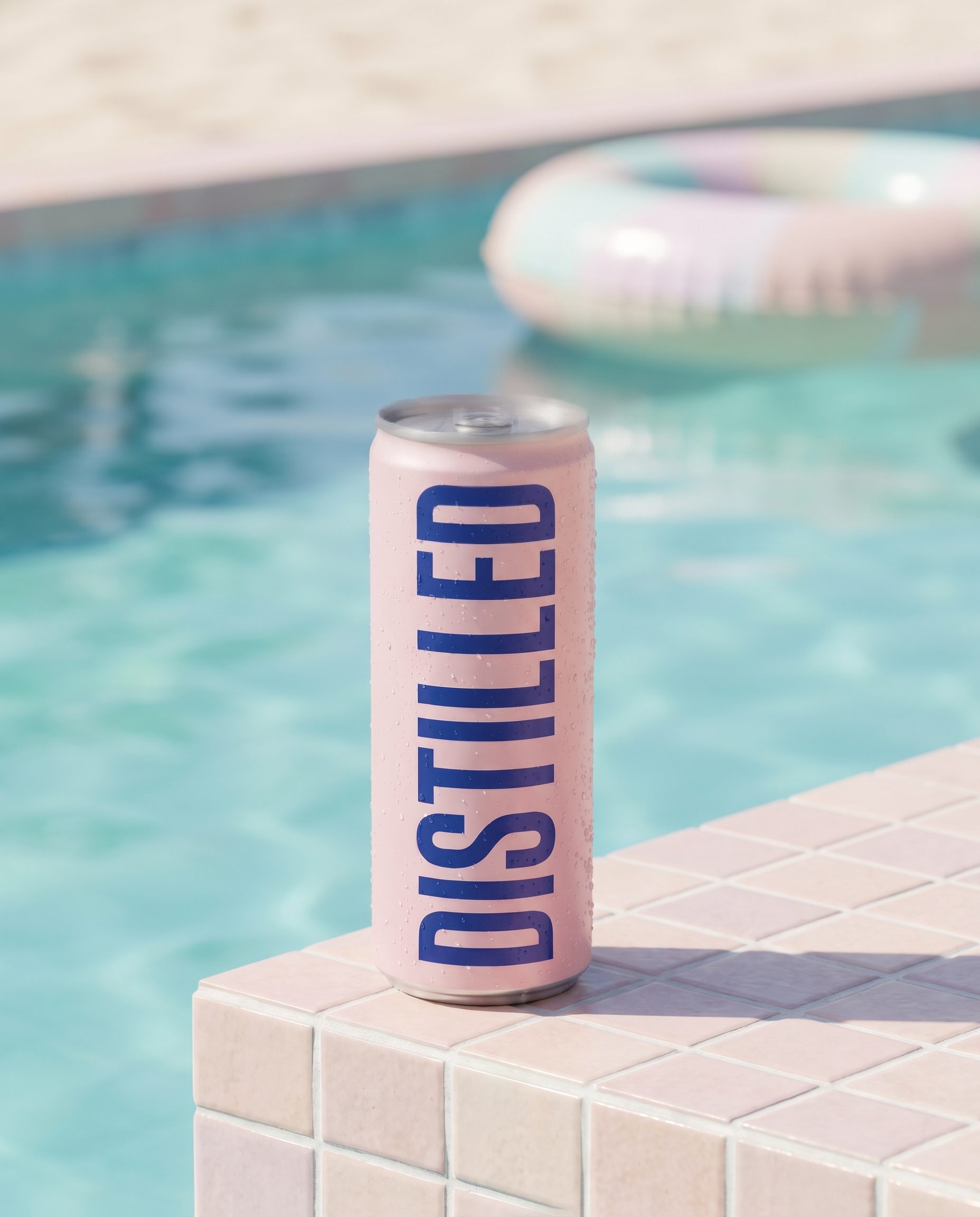 The can on a pastel poolside ledge, a life ring in the water behind