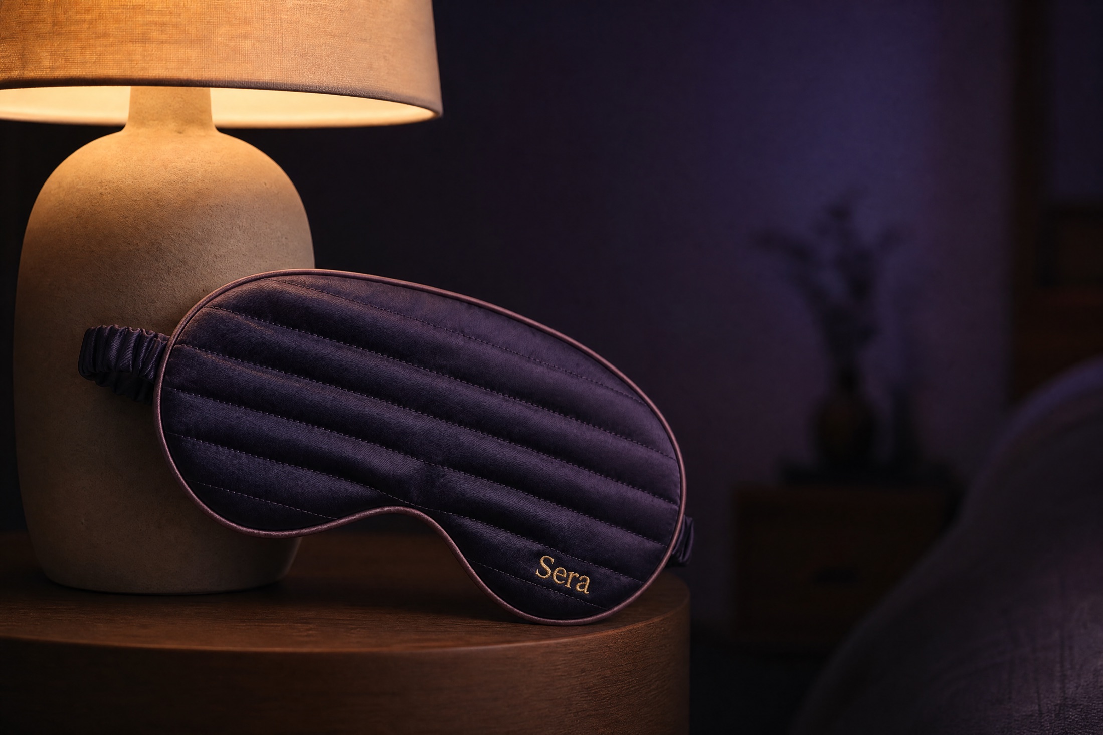 The mask draped by a warm ceramic bedside lamp in a twilight room