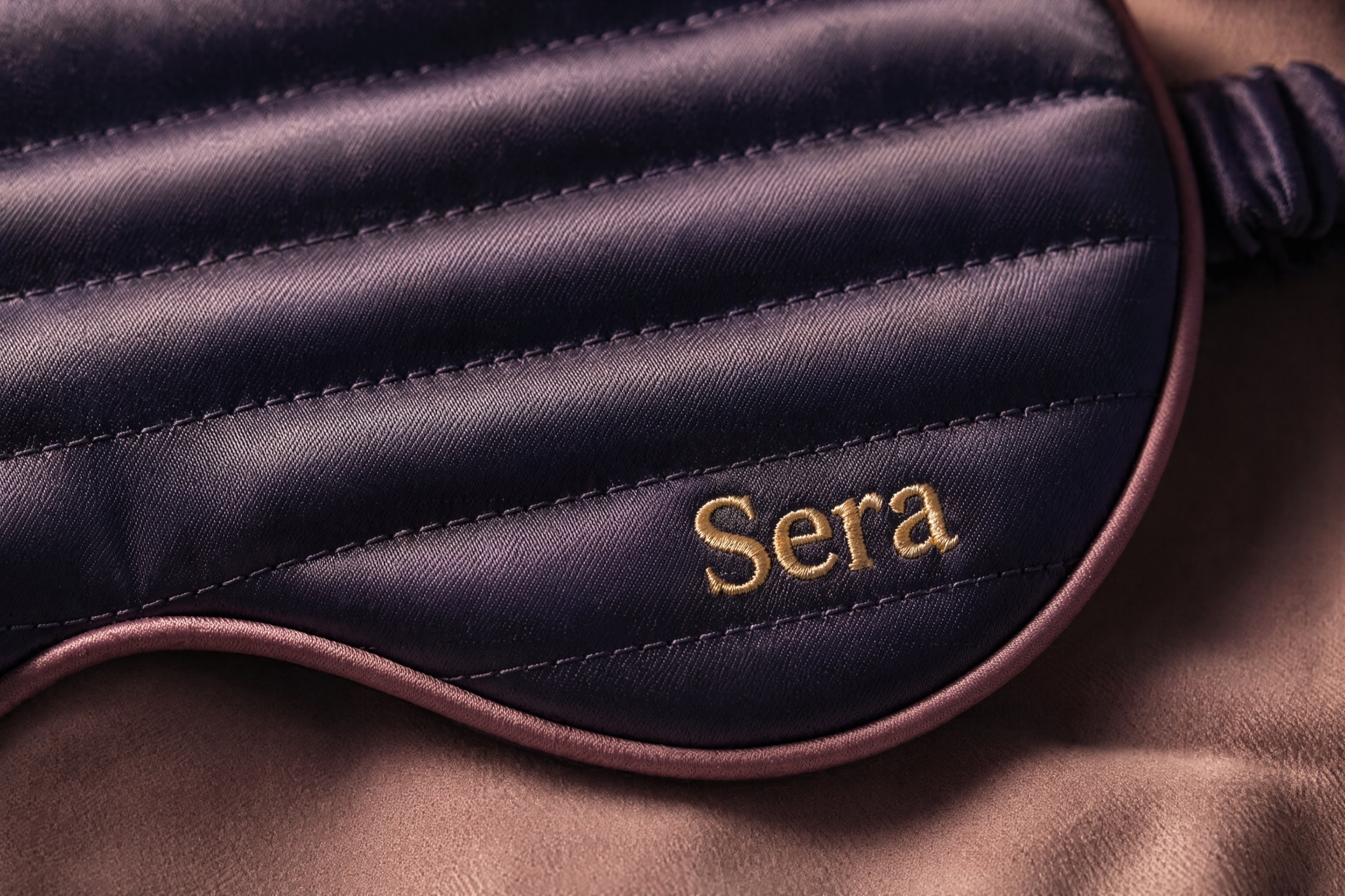 A macro of the quilted silk channels and the gold Sera wordmark in warm lamplight