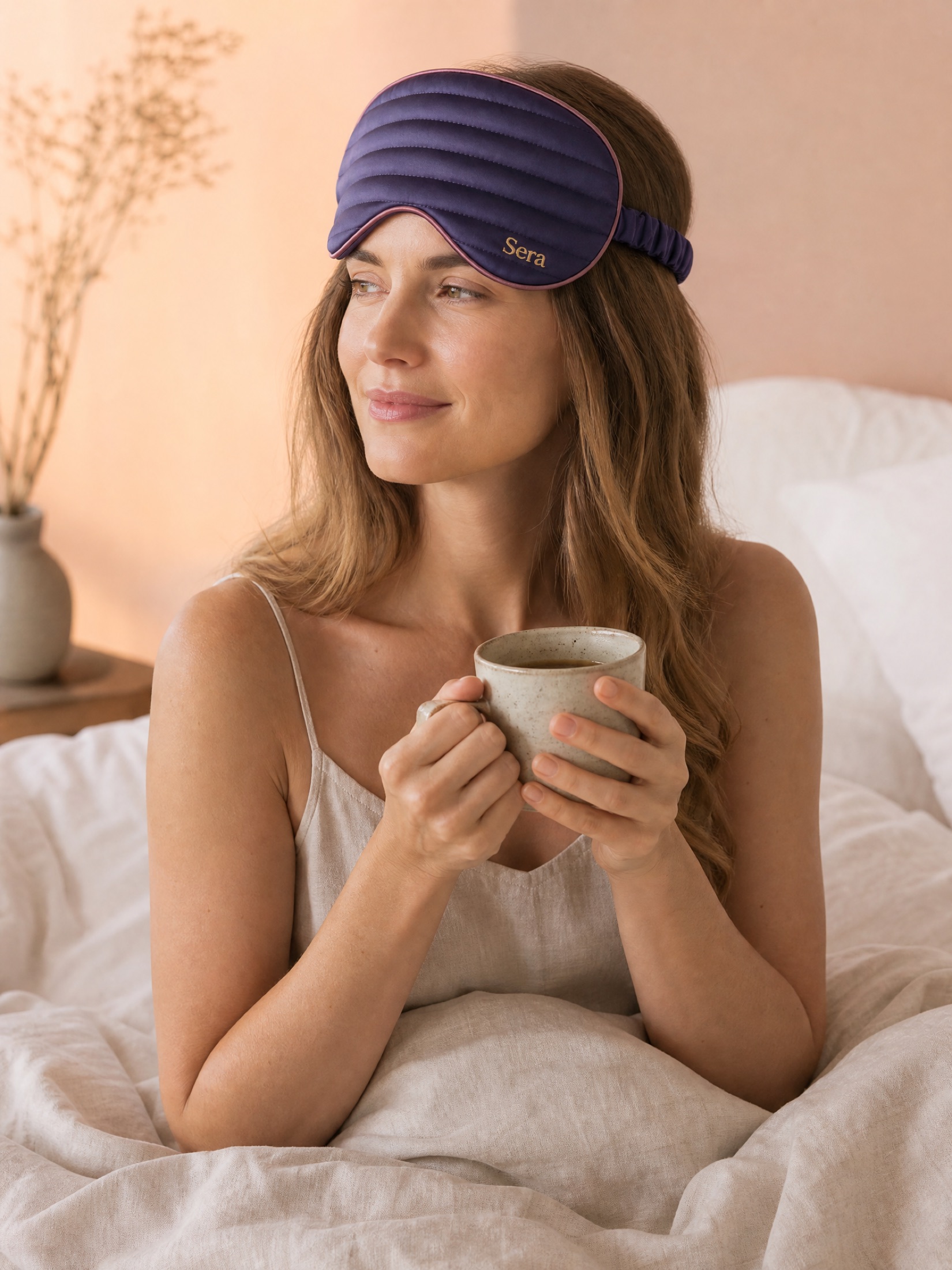 A woman waking with the mask on her forehead, holding a morning coffee