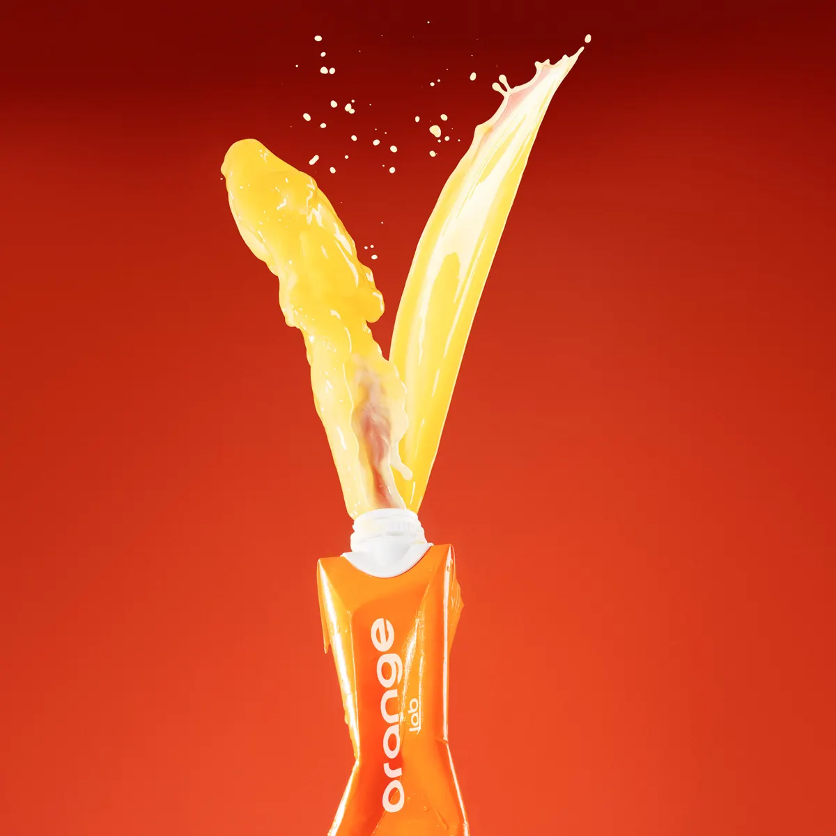 Orange juice carton bursting with a splash of juice on a red background.