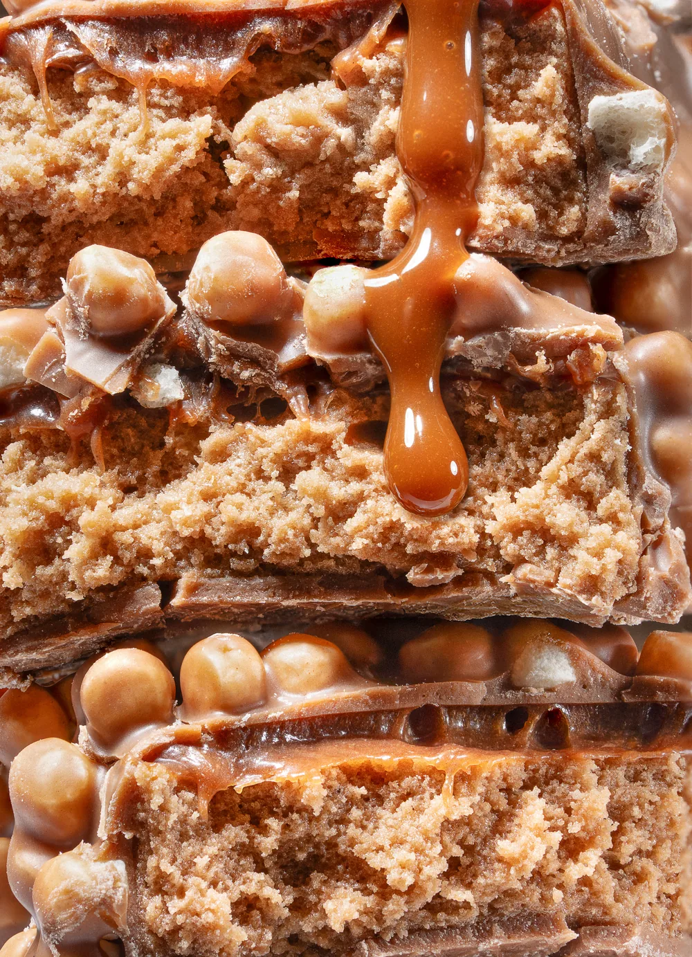 Macro of layered caramel and cookie bars with caramel poured over the stack.