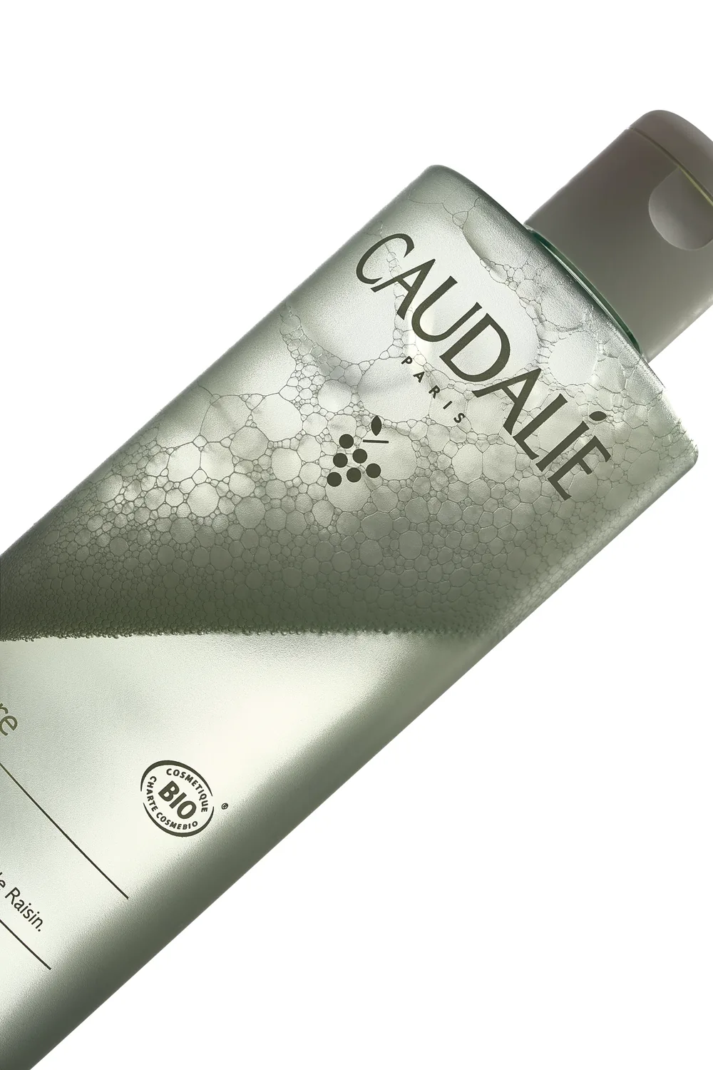 Close-up of a Caudalie Paris skincare tube with a frosted sage-green finish and Bio certification mark.