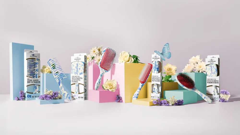 Denman Blue Belle brushes and pastel packaging arranged with spring flowers and a butterfly.