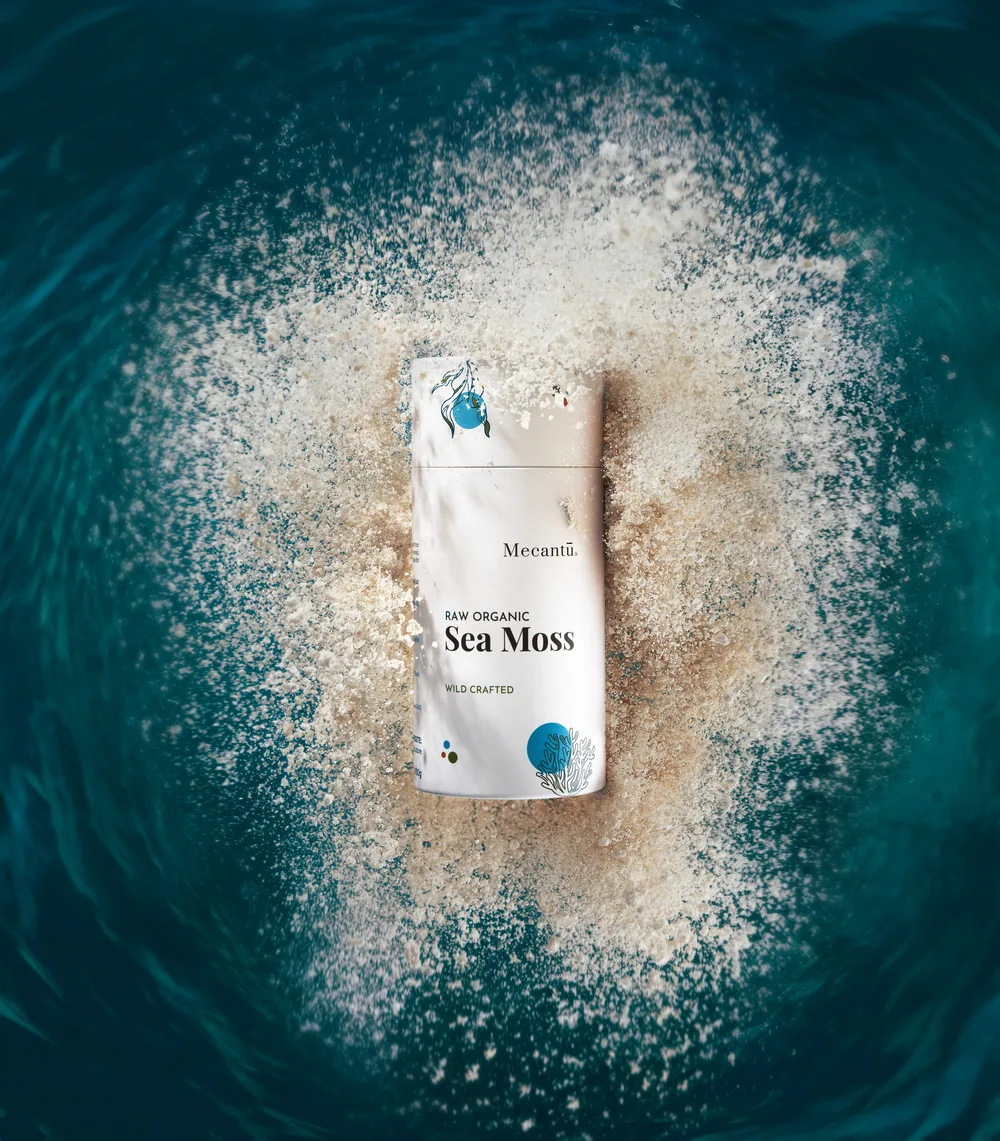 Mecantu Sea Moss sachet resting in a burst of sea salt against deep ocean water.