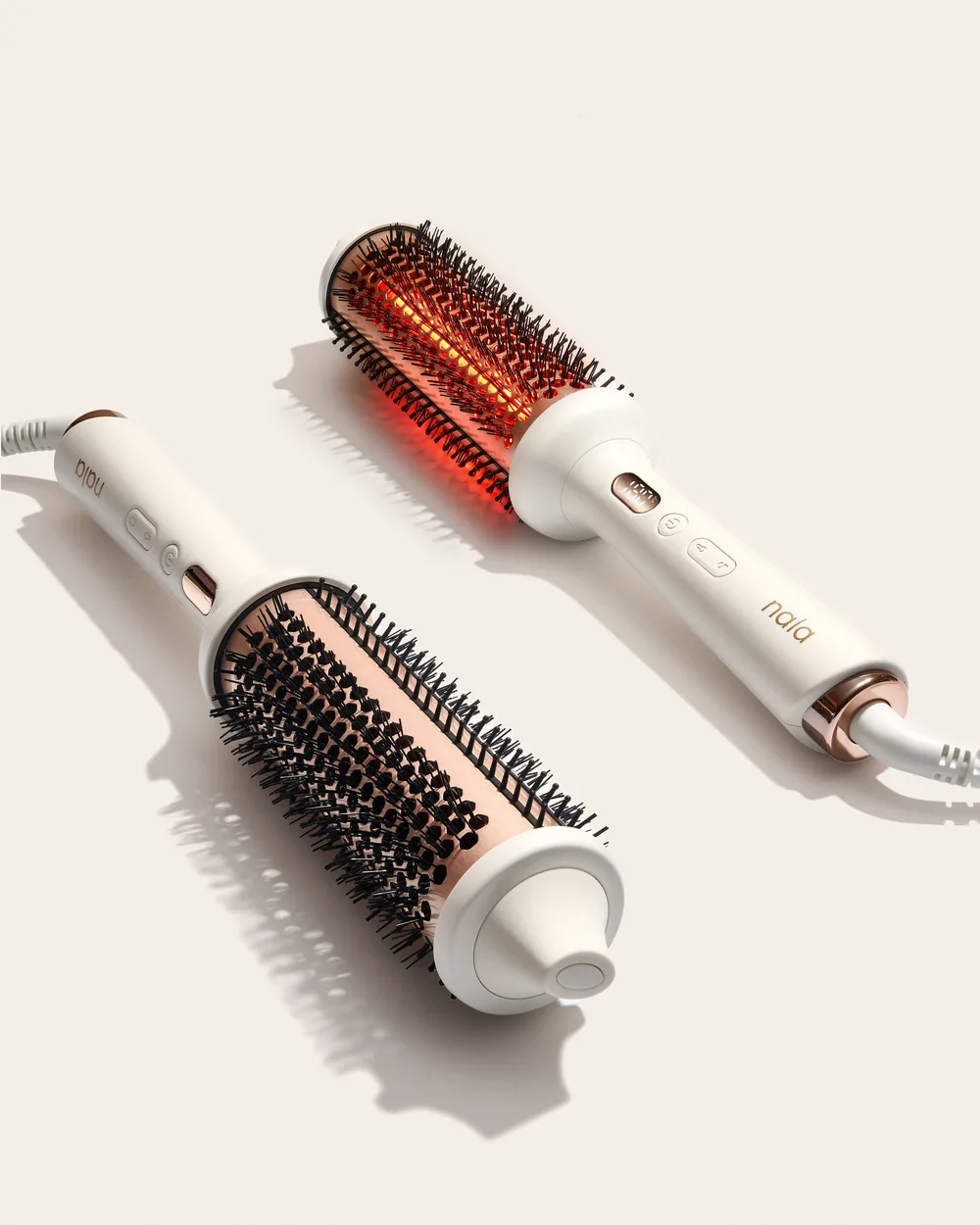 Two Nala Therma heated round brushes standing upright on a soft grey background.